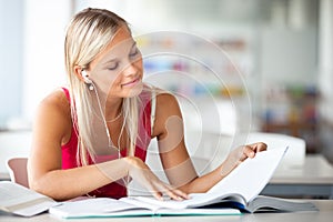 Pretty female student with books working in a high school library