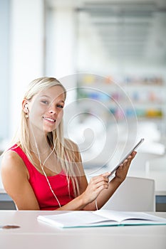 Pretty female student with books working in a high school library