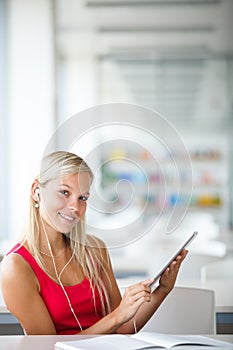 Pretty female student with books working in a high school library