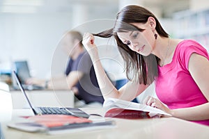 Pretty female student with laptop and books