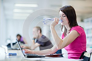 Pretty female student with laptop and books