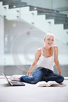 Pretty female student with laptop and books