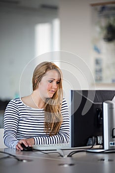 Pretty, female student looking at a desktop computer