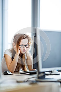 Pretty, female student looking at a desktop computer screen