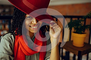 Pretty female student in red hat poses in cafe