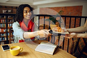 Pretty female student takes croissants in cafe