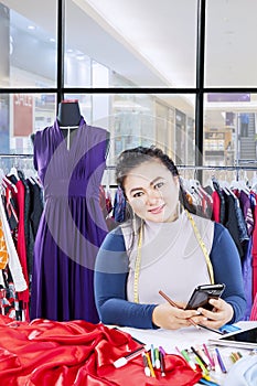 Pretty female tailor looking and smiling at camera