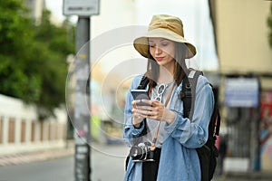 Pretty female traveler with backpack on holiday vacation trip in Thailand and using mobile phone for searching direction