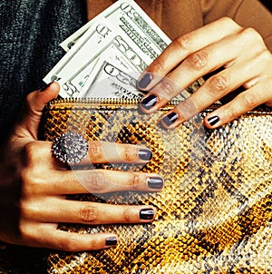 Pretty fingers of african american woman holding money close up with purse, luxury jewellery on python clutch, cash for