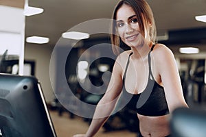 Pretty fit woman in black sportrswear training on a treadmill