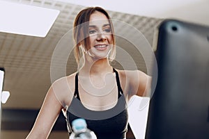 Pretty fit woman in black sportrswear training on a treadmill