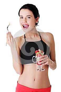 Pretty fit woman eating fruit salad