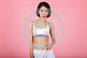 Pretty fit woman measuring her waist with a measuring tape. Healthy lifestyles concept