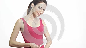Pretty fitness girl measuring her waist and smiling isolated