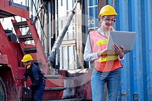 Pretty foreman woman stand with holding laptop for working in front of her co-worker fix the problem of vehicle in background of