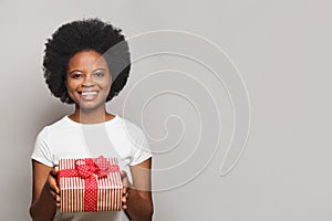 Pretty friendly positive smiling woman with red gift box looking at camera on white background