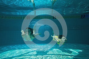 Pretty friends smiling and swimming underwater