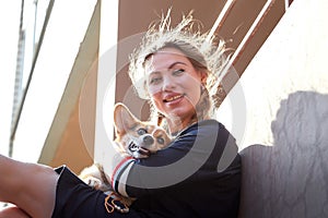 Pretty funny girl with small nice dog big wall of city house in a sunny day