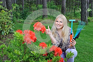 Pretty gardener woman with red flower bush