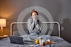 Pretty ginger girl or young woman is sneezing into a tissue