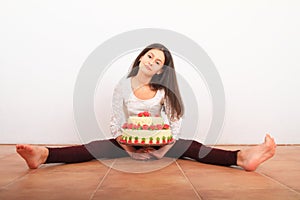 Pretty girl with anniversary cake sitting on floor