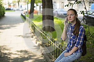 Pretty girl anxiously talking on the cell phone while sitting outdoors.