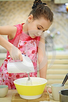 Pretty girl in apron prepares course with mixer in photo