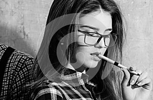 Pretty girl student in nerd glasses holding pen in mouth