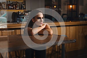 Pretty girl behind bar table and lay down her chin on crossed hands