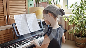 Pretty girl blogger playing classic digital piano and recording video like online concert at home