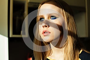 Pretty girl with blonde hair and blue eyes makeup on sun ligth and shadows