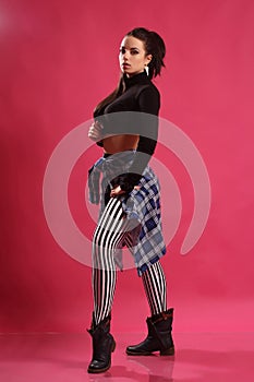 A pretty girl brunette fitness instructor, trainer, dancer go go, posing in the studio on a pink background