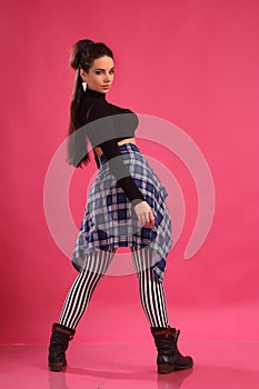 A pretty girl brunette fitness instructor, trainer, dancer go go, posing in the studio on a pink background