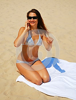 Pretty girl calling with a mobile on the beach.