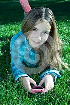 Pretty girl with cell phone laying on grass