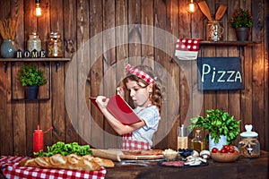 Pretty girl in checkered apron reading recipes book