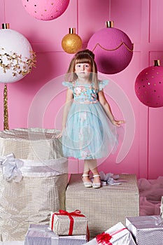 Pretty girl child 4 years old in a blue dress. Baby in Rose quartz room decorated holiday.