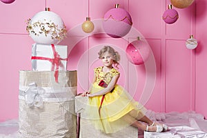 Pretty girl child 6 years old in a yellow dress. Baby in Rose quartz room decorated holiday.