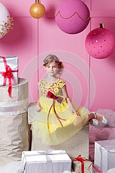 Pretty girl child 6 years old in a yellow dress. Baby in Rose quartz room decorated holiday.