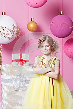 Pretty girl child 6 years old in a yellow dress. Baby in Rose quartz room decorated holiday.