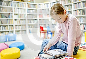 Pretty girl child reading book in library