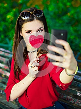 Pretty girl with colorful lollipop is taking selfies