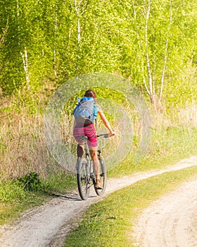 Pretty girl cycling in the wild nature on dirt road. Bikes cycling girl. Girl rides bicycle.