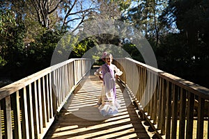 A pretty girl dancing flamenco in a typical gypsy dress with frills and fringes walks on a wooden bridge in a famous park in