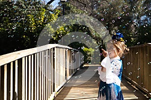 A pretty girl dancing flamenco in a typical gypsy dress with frills and fringes walks on a wooden bridge in a famous park in