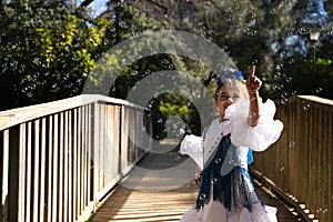 A pretty girl dancing flamenco in a typical gypsy dress with frills and fringes walks on a wooden bridge in a famous park in