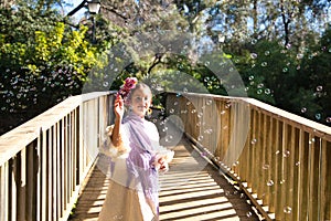 A pretty girl dancing flamenco in a typical gypsy dress with frills and fringes walks on a wooden bridge in a famous park in photo