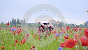 Pretty girl dancing in a poppy field smiling happily. Connection with nature. Leisure in nature. Blossoming poppies