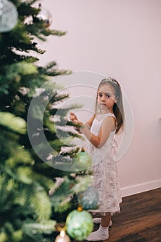 Pretty girl decorating Christmas tree with baubles