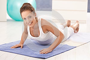 Pretty girl doing gymnastics on floor at home